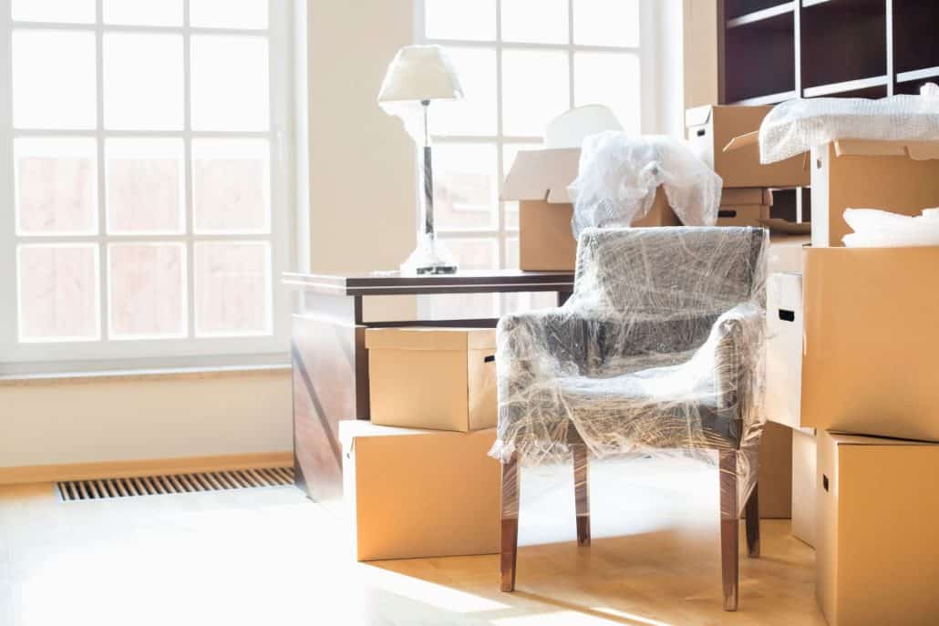 Furniture protected by plastic sheeting, surrounded by boxes